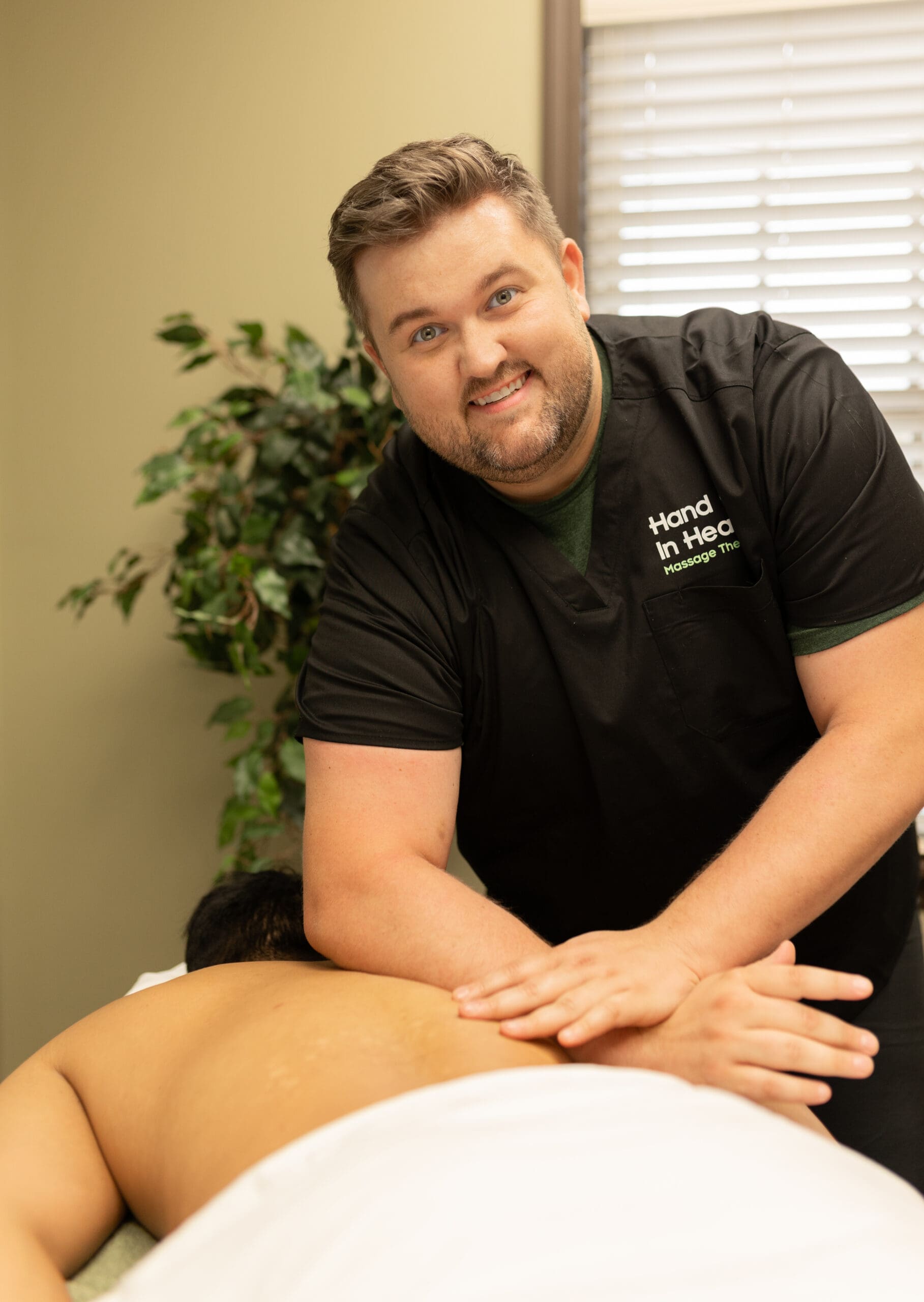 Hand in Health massage therapist smiling while giving a patient a back massage in Syracuse, NY