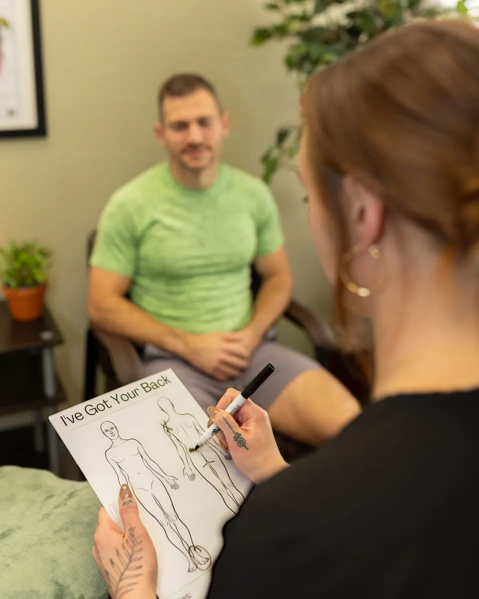 Hand in Health massage therapist reviewing a body chart with a patient before treatment in Syracuse, NY