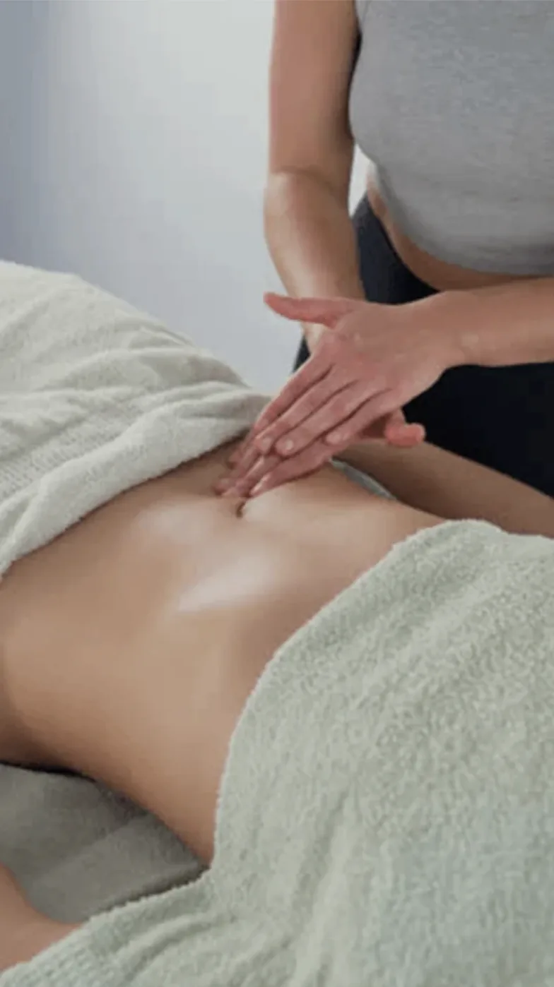 Therapist's fingertips resting lightly on a patient's abdomen during gentle lymphatic drainage