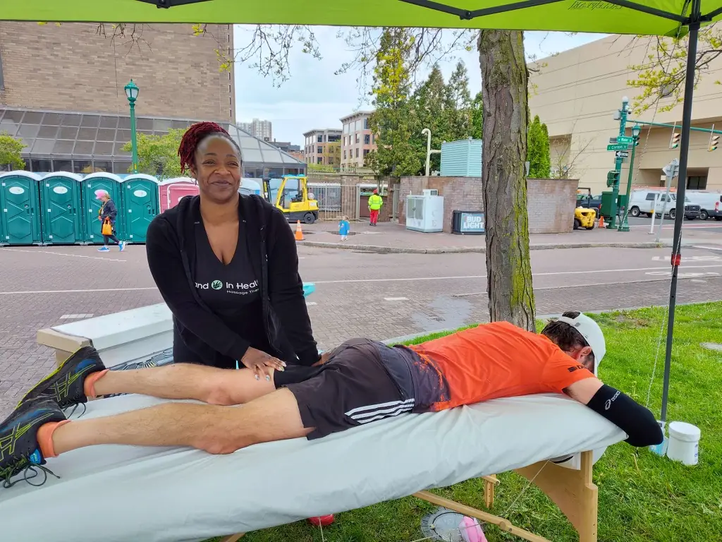 Hand in Health massage therapist giving a runner a free post-race sports massage at the Mountain Goat Run in Syracuse
