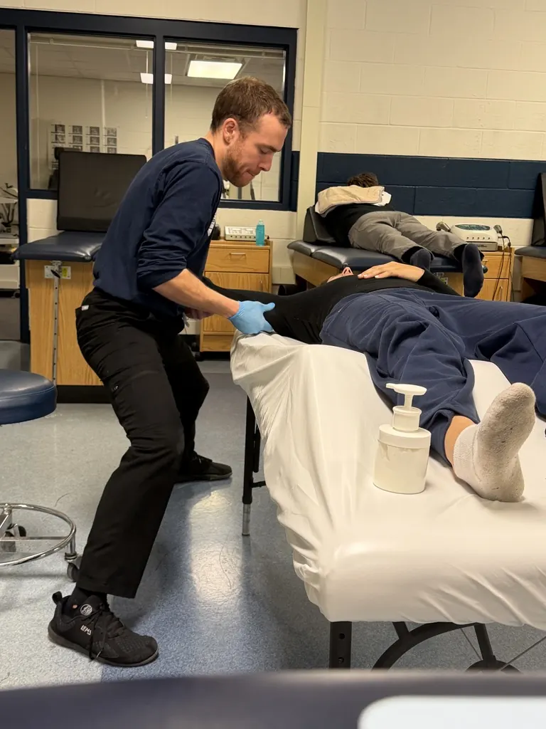 Hand in Health massage therapist treating an athlete in a Syracuse University athletic training room